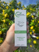Hand holding a box of ZenPaw CoatRestore against a blurred natural background with yellow flowers.